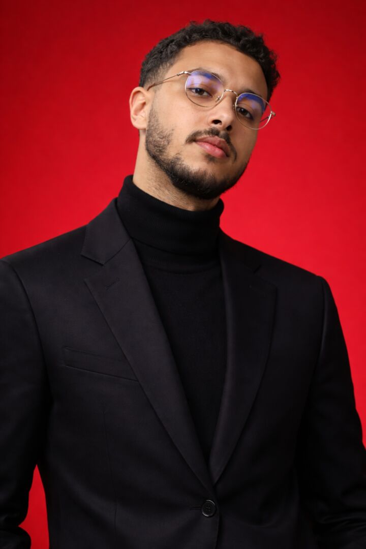 Portrait of Othmane Jamali El Alaoui on a red background — black suit and turtleneck